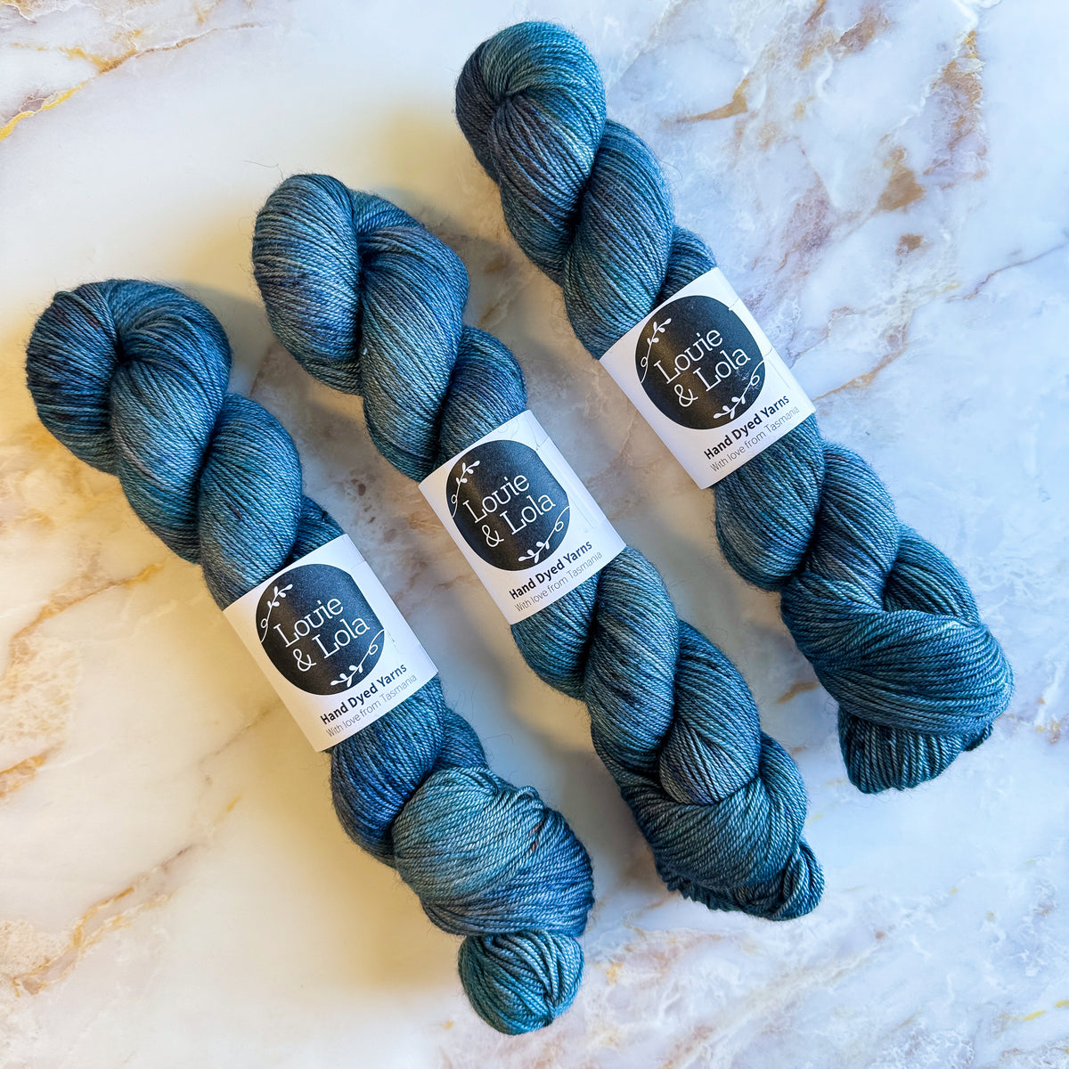 Three skeins of blue yarn on a marble surface.