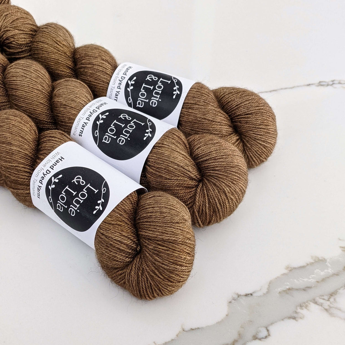 Three skeins of brown yarn labeled Louie & Lola on a light background, perfect for knitting or crochet projects.