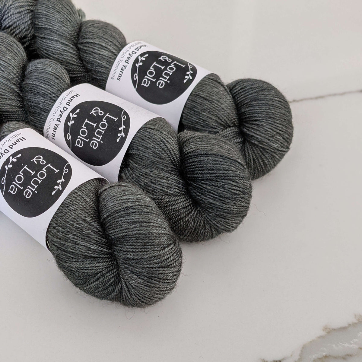 Gray skeins of yarn with labels arranged on a white surface.
