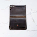 Brown leather tablet case with a foldable cover and magnetic closure, displayed on a marble surface.