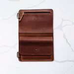 Brown leather wallet open on white marble surface with multiple compartments and button closure.