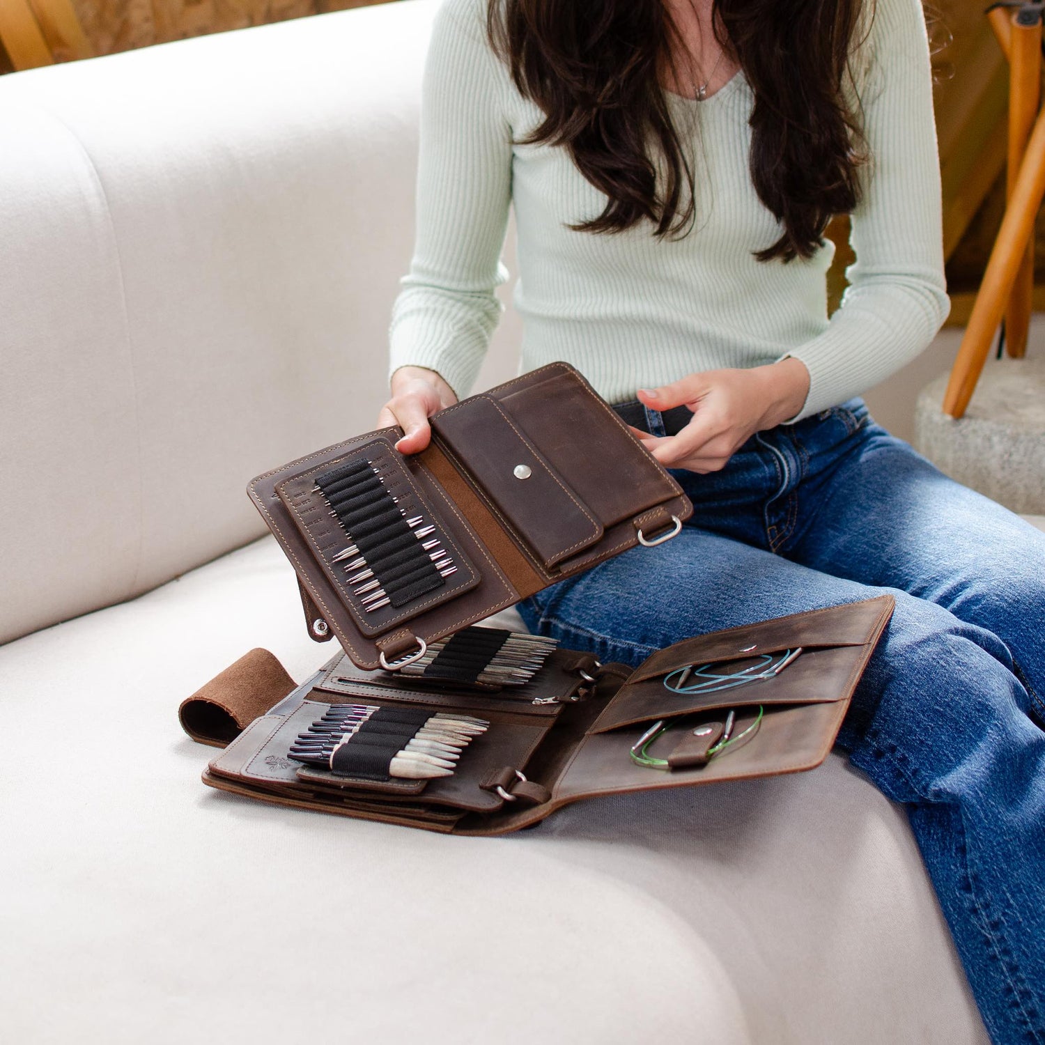 Woman sitting on a white couch organizing multiple wallets containing credit cards and cash.