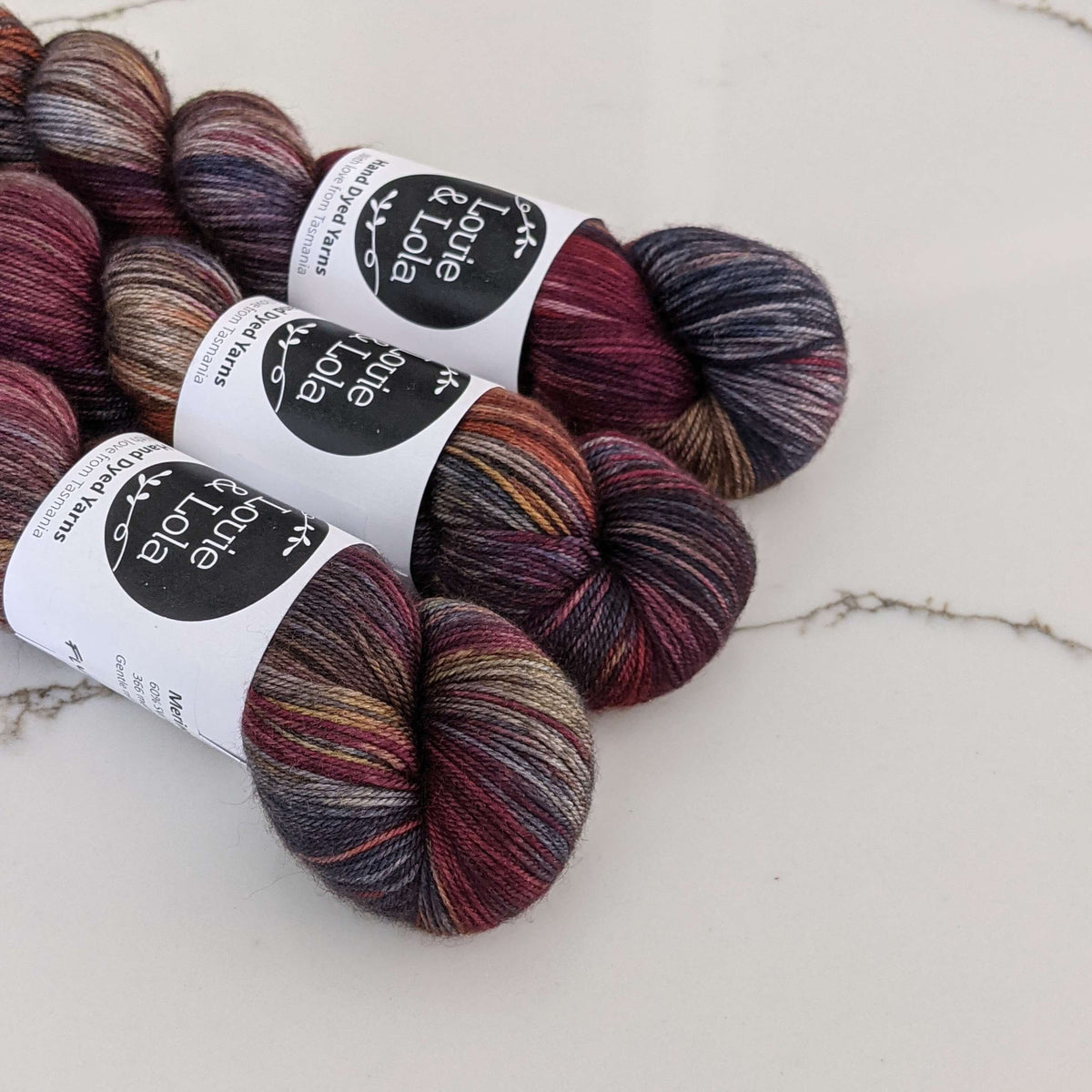 Colorful skeins of yarn with labels on a marble surface.