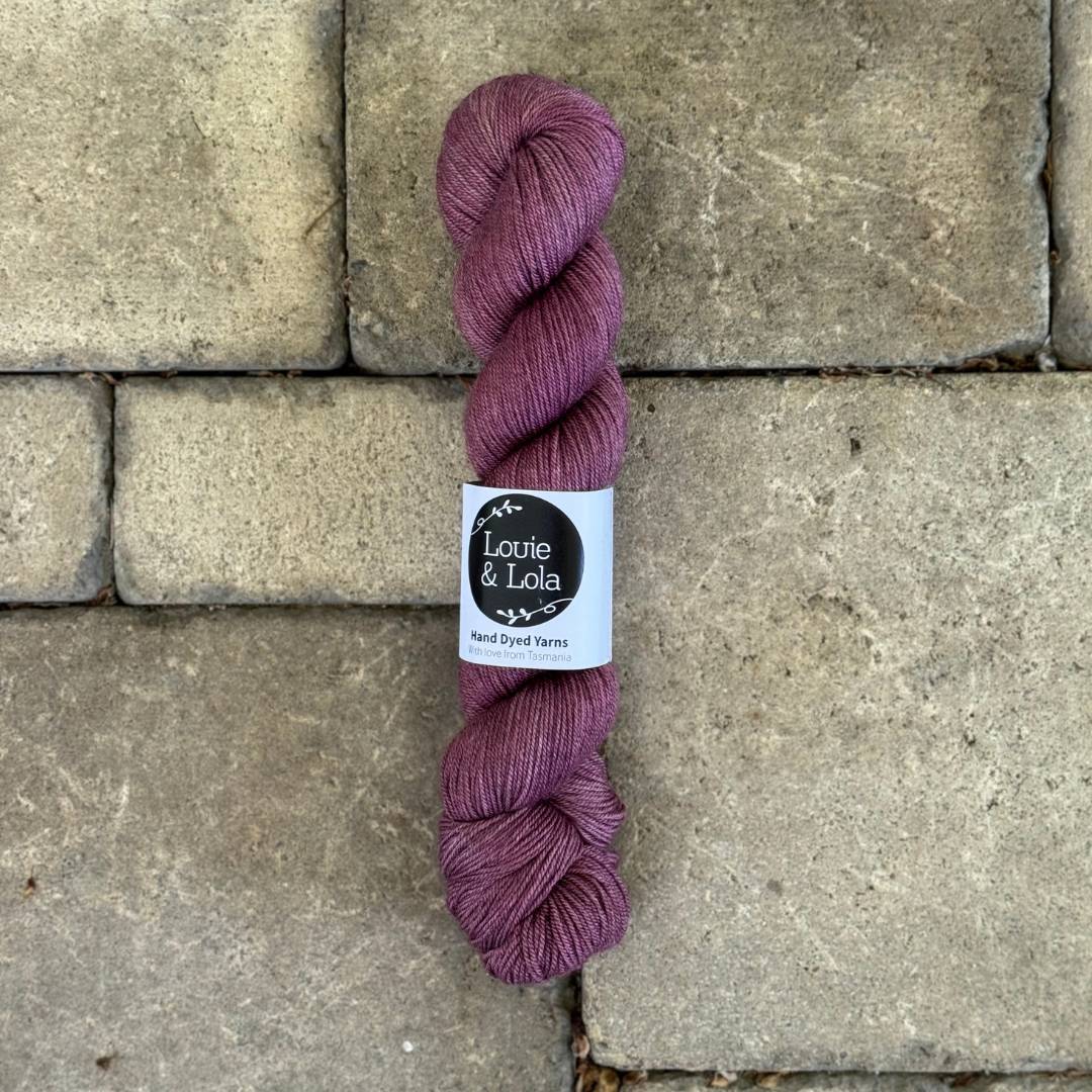 Purple skein of yarn on a stone tile background.