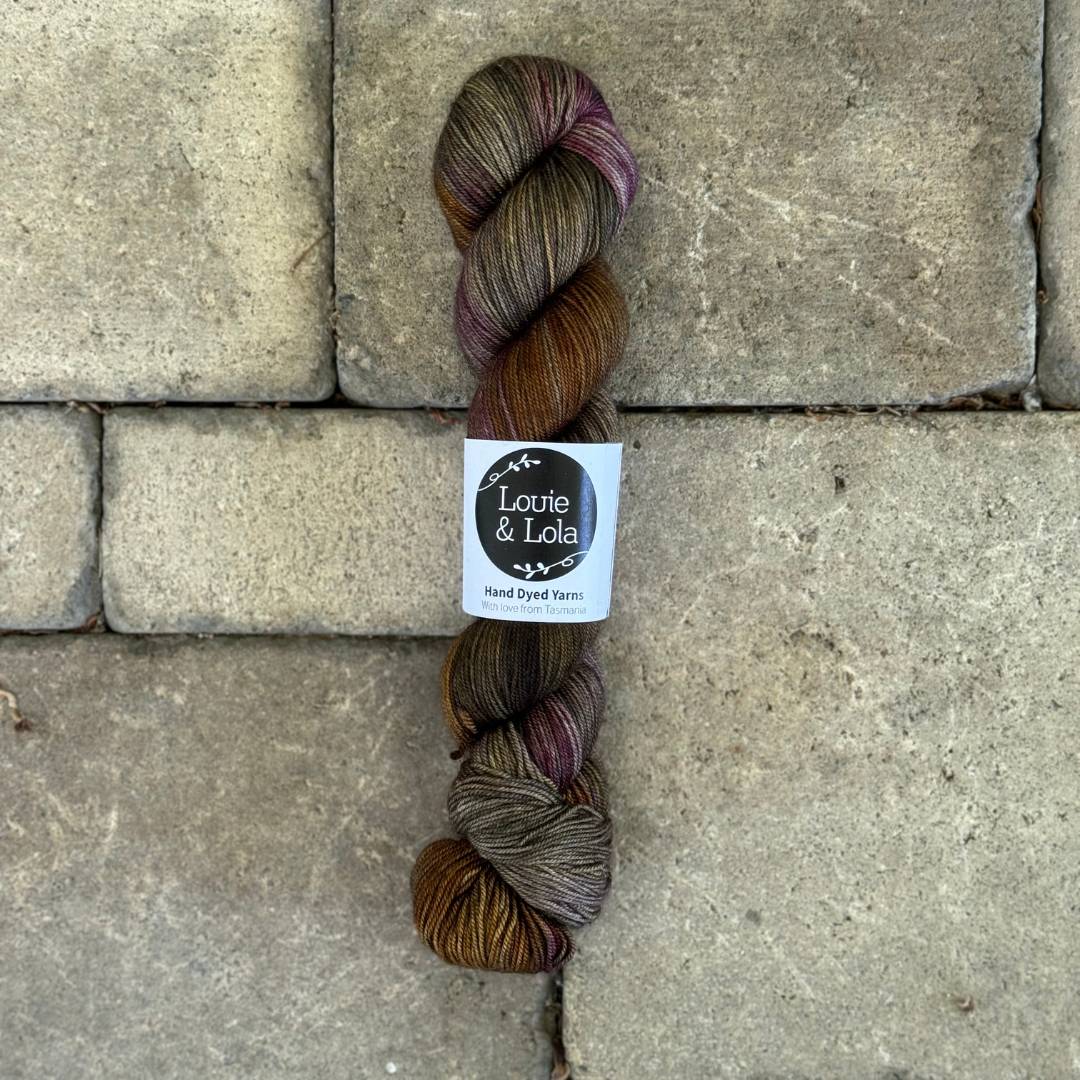 Skein of brown and purple yarn on stone tile background