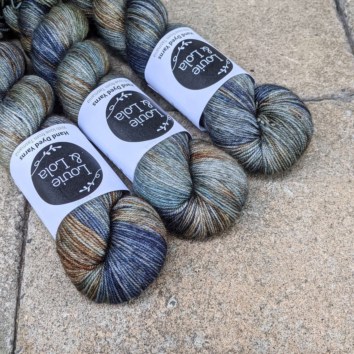 Skeins of multicolored yarn with labels on a textured surface.
