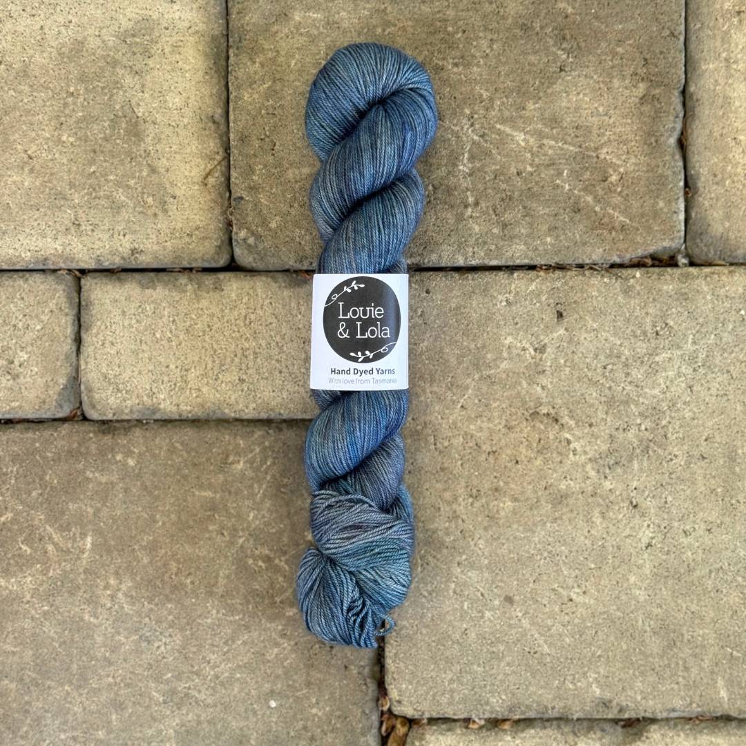 Blue yarn skein on stone pavement background.