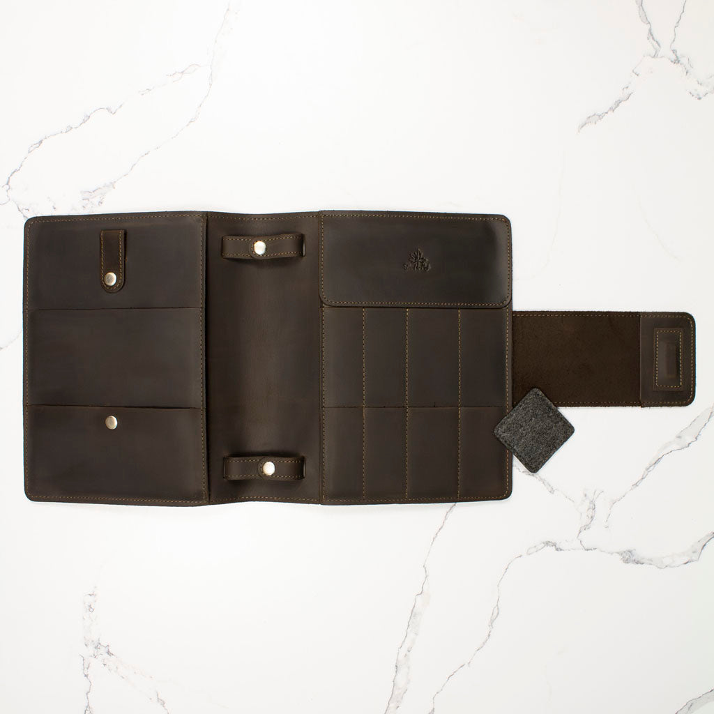 Open brown leather wallet with multiple compartments on a white marble surface.