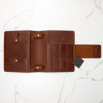 Brown leather bifold wallet with multiple card slots and coin pocket on white marble background