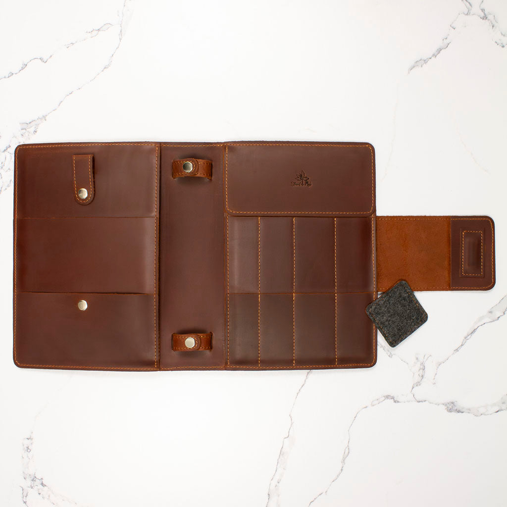 Open brown leather wallet with multiple card slots and compartments on a marble surface.