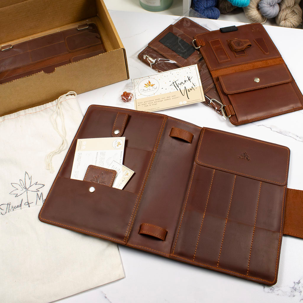 Brown leather wallet set with card slots and compartments, gift box and cloth bag, displayed on white table.