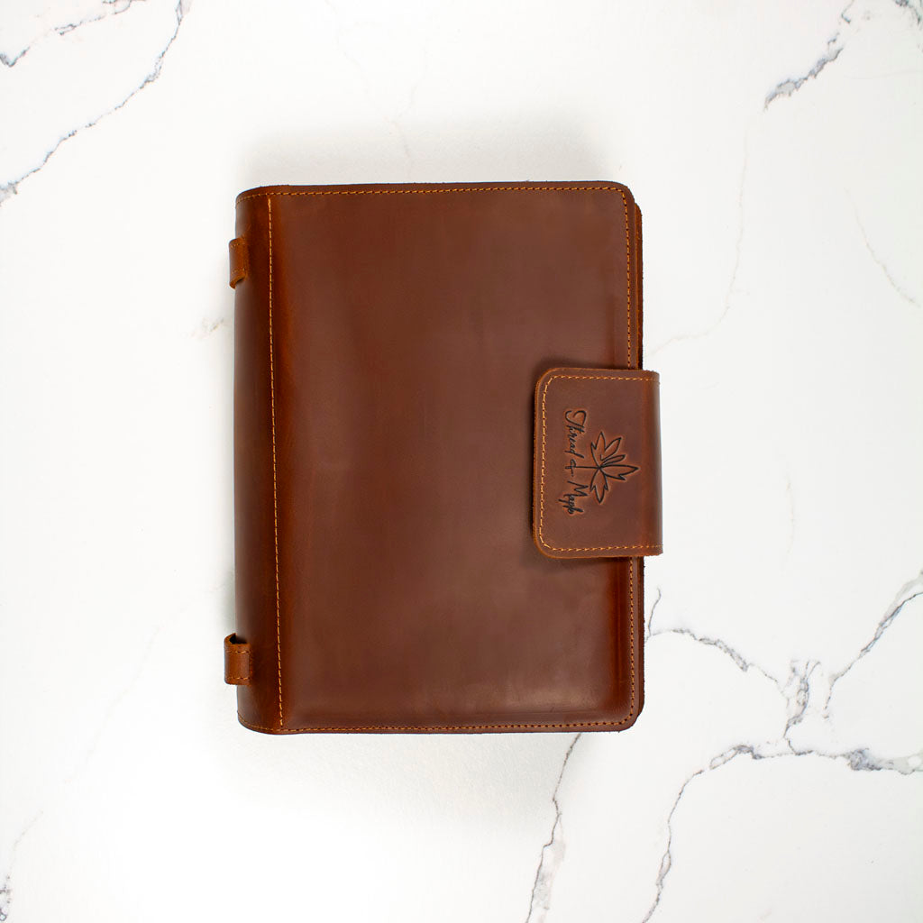 Brown leather wallet with embossed logo on white marble background.
