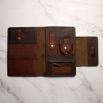 Leather travel wallet organizer open on marble surface showing compartments and pockets for cards and documents