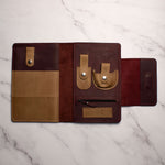 Open leather travel wallet with multiple compartments and organizers on a marble surface.