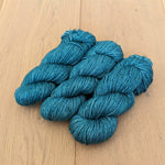Three skeins of teal yarn on a wooden surface.