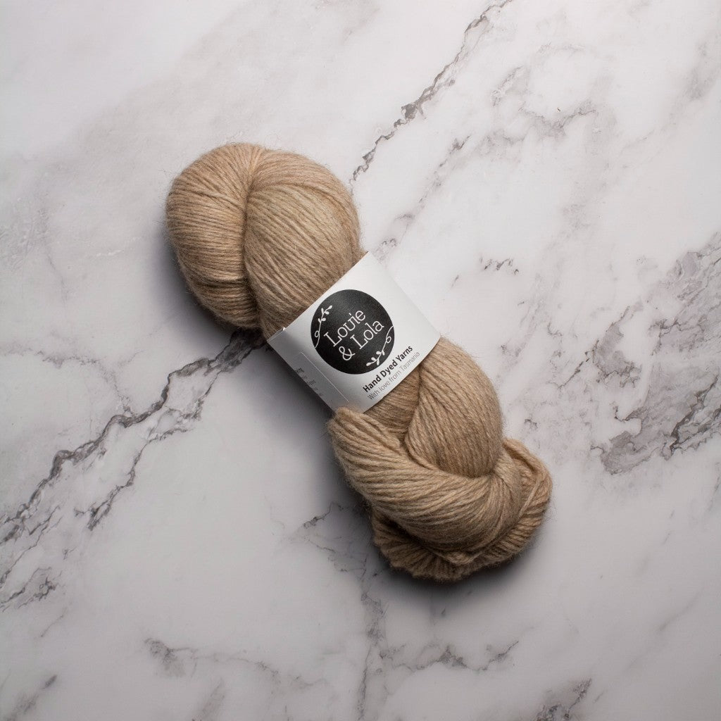 Beige skein of yarn on a marble surface.